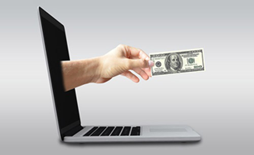 Hand with money emerges from laptop