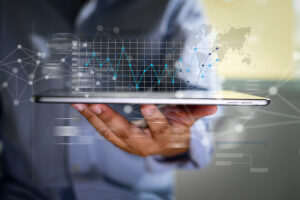 a hand holding a tablet with charts coming out of the screen